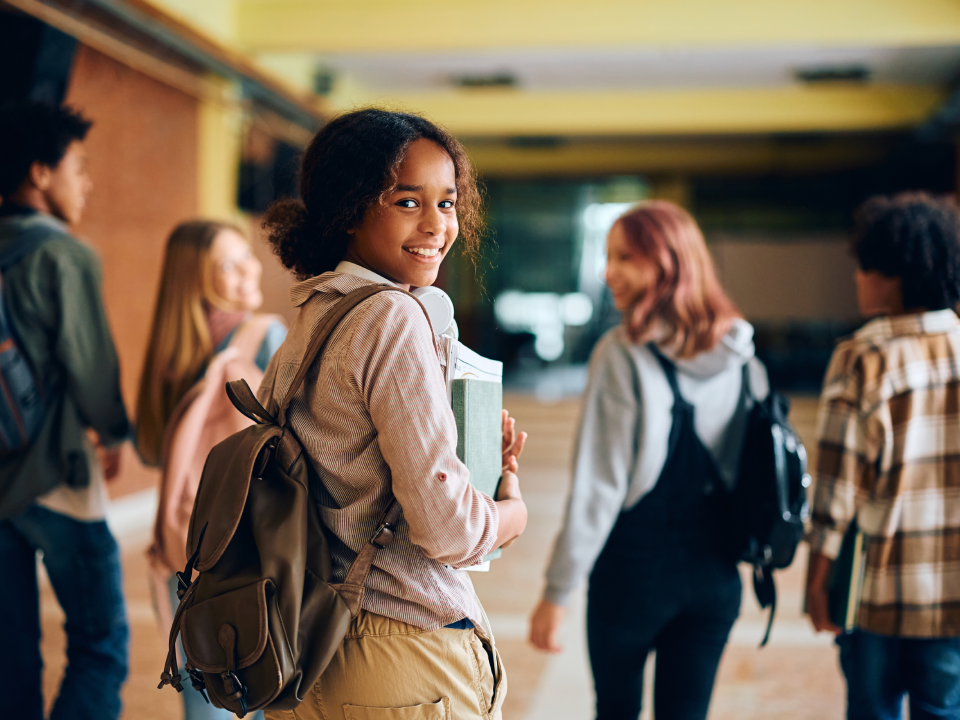 Saúde mental na educação: grupo de estudantes adolescentes andando juntos no corredor enquanto uma das meninas sorri.