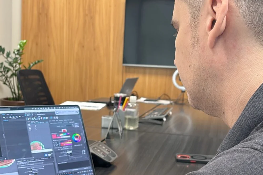 Profissional de perfil diante de um notebook com painel de dados na tela
