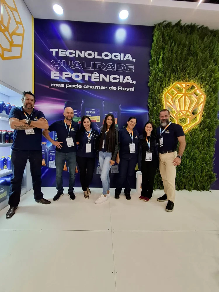 Equipe posando em estande de feira, diante do painel escrito Tecnologia