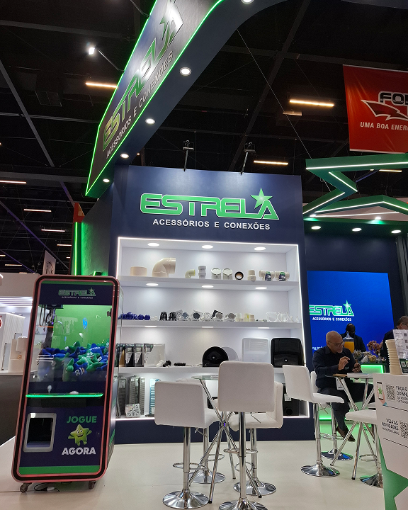 Vista interna do estande da Estrela, com produtos expostos e telão